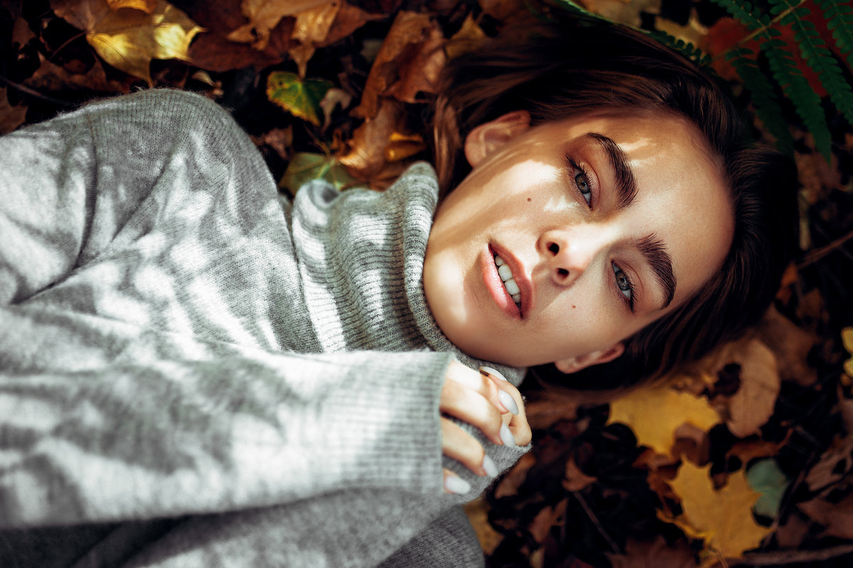 Девушка в свитере лежит на земле, усыпанной разноцветными осенними листочками - Lenar Abdrakhmanov