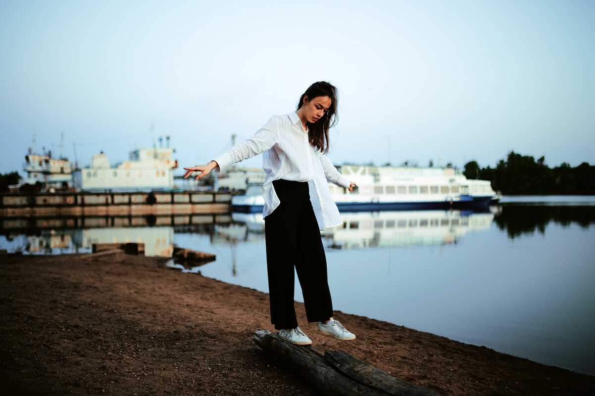 Девушка в белой рубашке идет по бревну на закате на фоне реки с кораблем - Lenar Abdrakhmanov