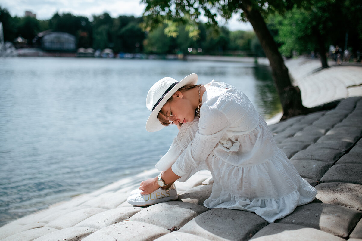 Девушка в белом платье и белой шляпе сидит на берегу пруда в парке - Lenar Abdrakhmanov