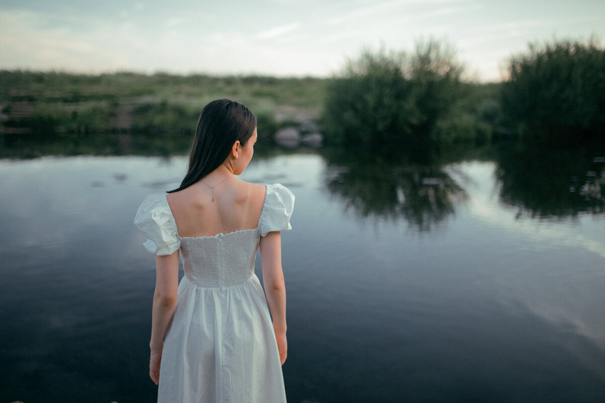 Девушка в белом платье стоит на берегу голубого озера летним вечером - Lenar Abdrakhmanov
