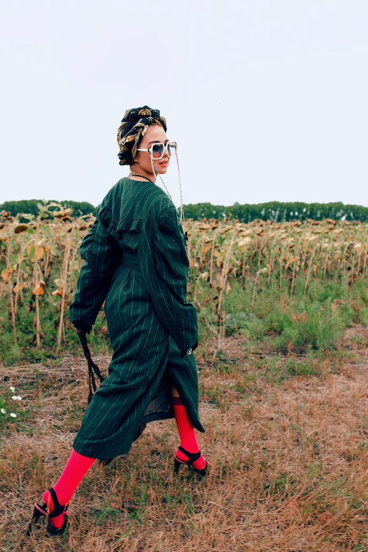 Девушка в стильной дизайнерской одежде идет на фоне засохших подсолнухов с сумкой в руке - Lenar Abdrakhmanov