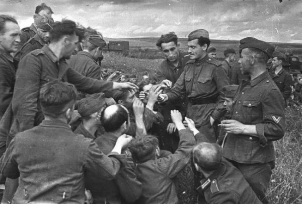 Советский солдат дает закурить немецким пленным. 1943 год.