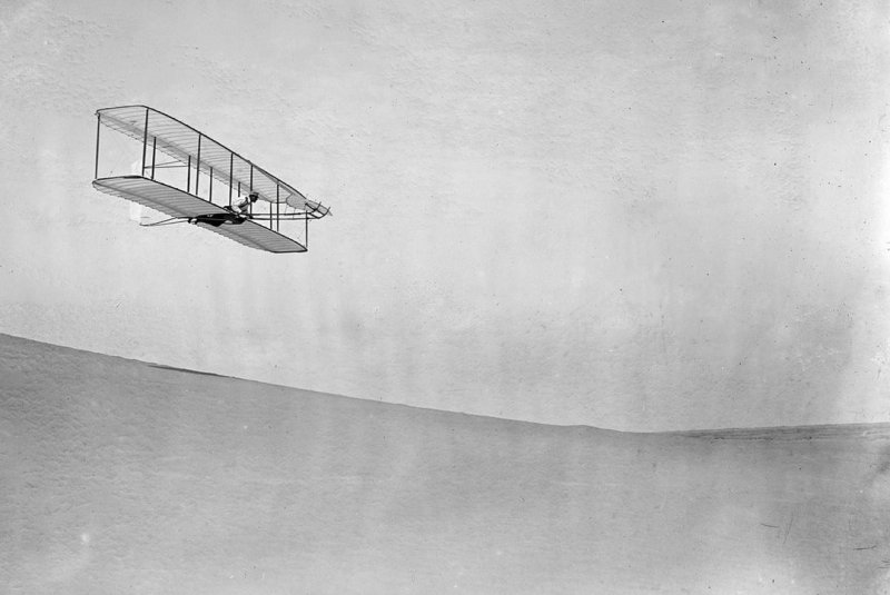 Уилбур Райт пилотирует планер вниз по крутому склону.