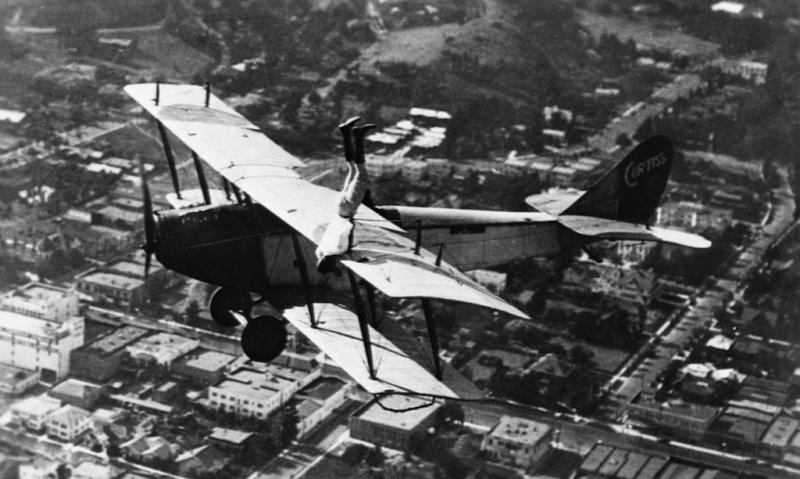 Каскадер Ормер Локлир делает стойку на руках на крыле биплана Curtiss JN-4D в 1920 году.